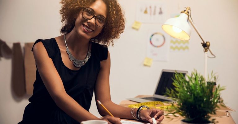 21 Days to Healthier Finances - picture of female freelancer at her desk smiling at camera