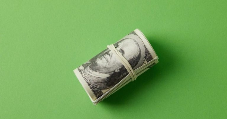 3 Big Mistakes Couples Make With Money - picture of roll of bills secured with rubberband on green background