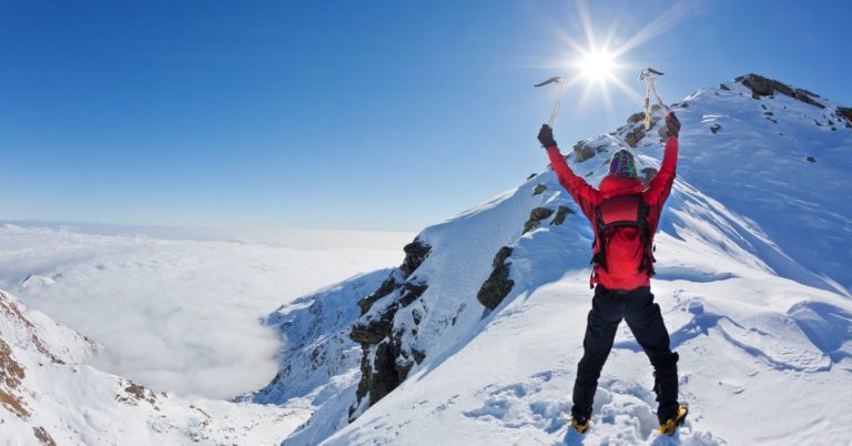 Debt snowball - picture of man celebrating at top of snowy mountain