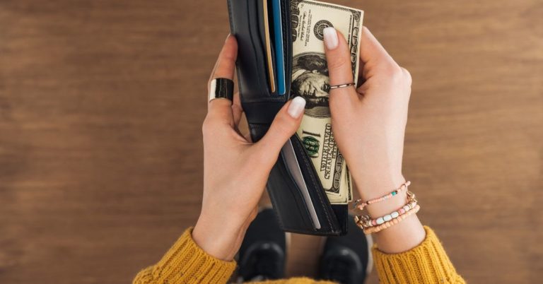 Do You Feel Comfortable Sharing Your Income - picture of top view of woman pulling cash out of wallet