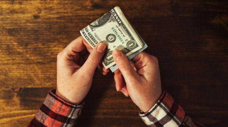 image of man's hands holding a stack of $1 bills