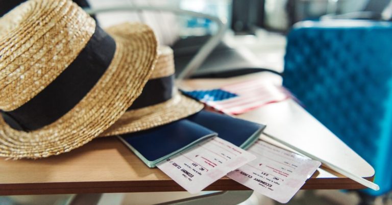 How to Go On Vacation without Losing Your Mind - picture of hats, passports, and other travel documents on table