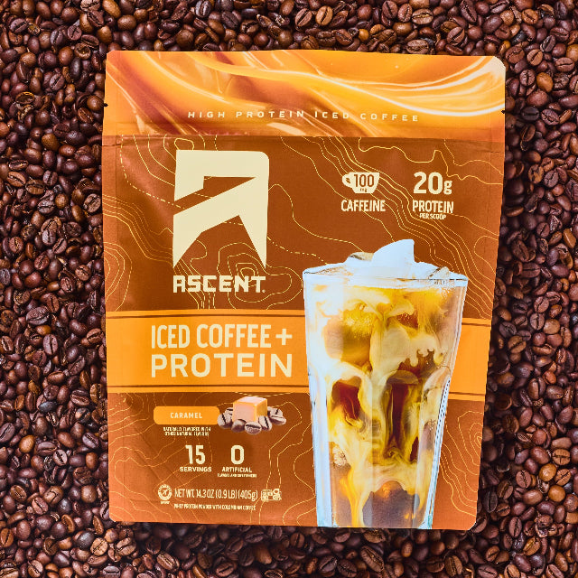 A bag of Caramel Iced Coffee + Protein laying on top of a layer of coffee beans