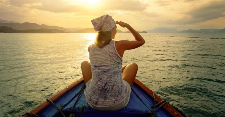 One Year Lived A Club Thrifty Review - picture of woman overlooking edge of boat toward sunset