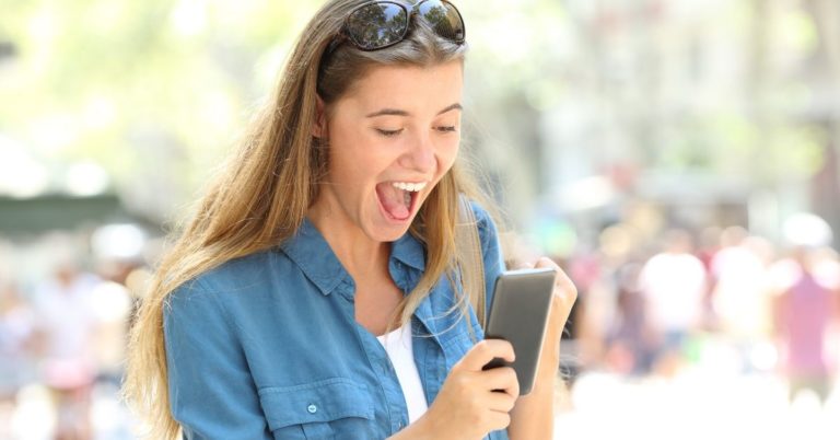 Republic Wireless Review - picture of young woman excitedly reading cell phone