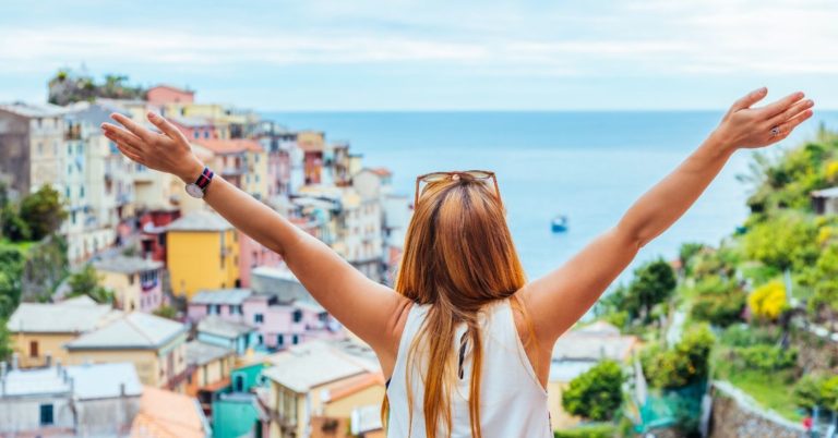 Roofstock Review - picture of young woman overlooking foreign city on water with hands raised