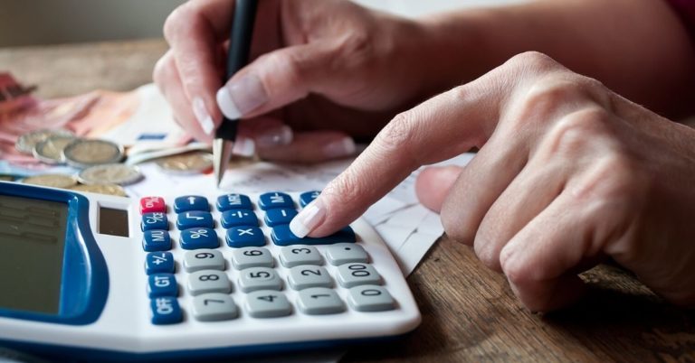 Simple Strategies for Reducing Debt - up close picture of hand on calculator and with pen