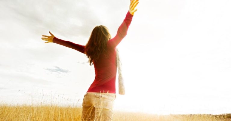 The 5 Financial Habits that Changed My Life - picture of woman with outstretched arms in field