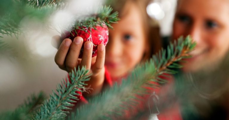 Tips for Financially Surviving the Holidays - picture of girl handing ornament on Christmas tree