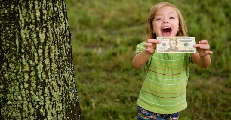 What I Want to Teach My Kids About Money_picture of young happy girl with 20 dollar bill in her hands