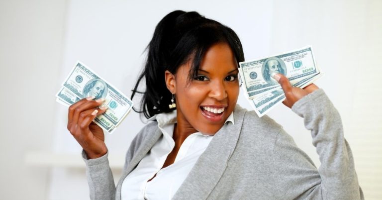 Why Saving Money Feels as Good as Spending Does - picture of woman smiling and holding up cash